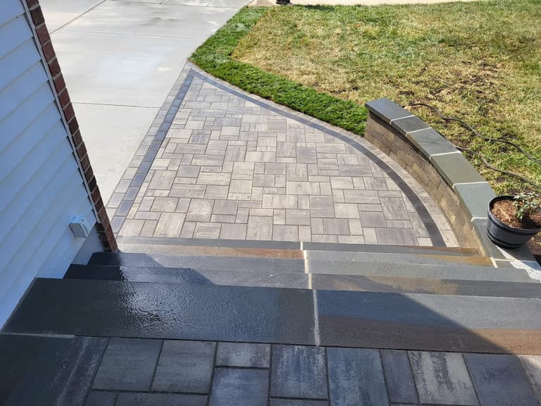 After — the paver landing meeting the driveway, with the soldier-course border tying the two together