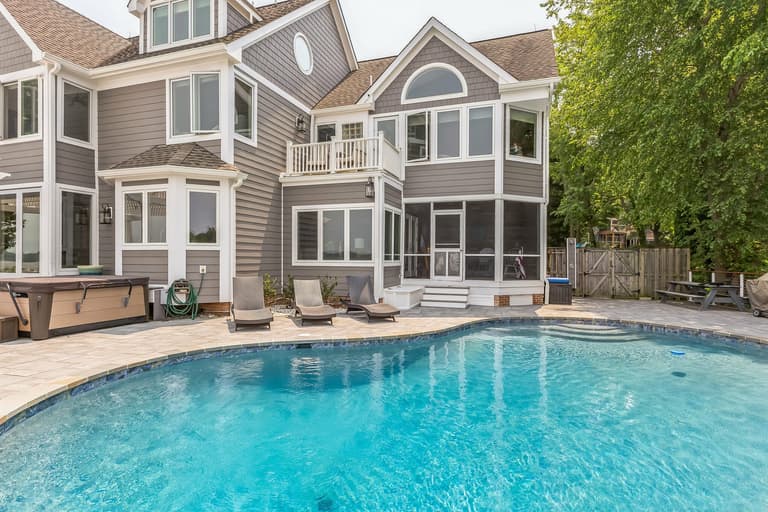 The spa set into the paver deck beside the pool, against the rear of the house